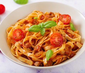 Pasta Fettuccine Bolognese with tomato sauce in white bowl.