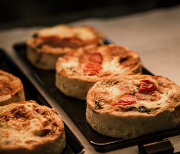 Small puff pies with vegetables and meat, quiches in a cafe window close up.