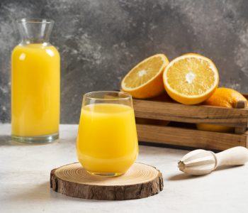 A glass cup of fresh orange juice on a wooden board. High quality photo